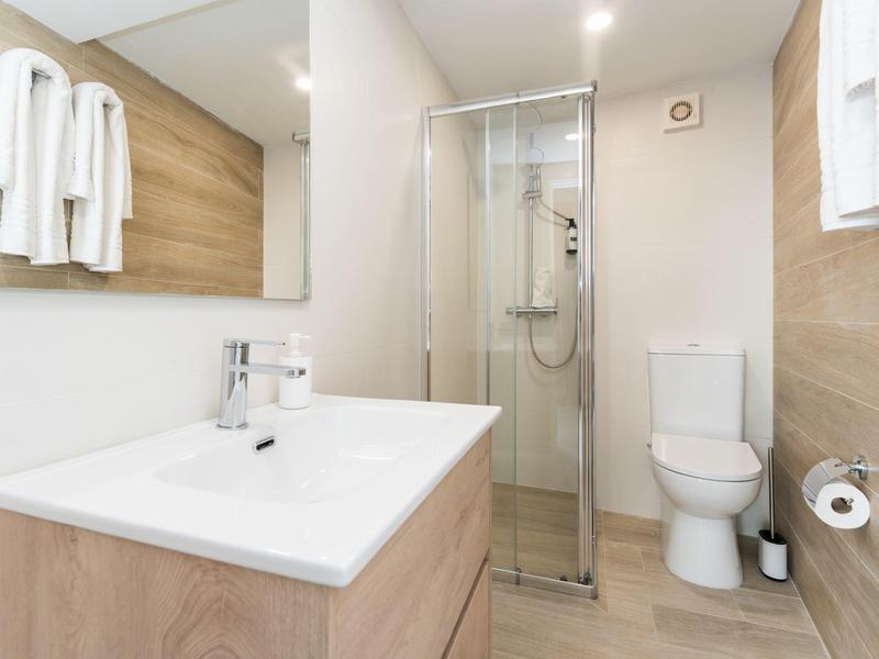 Nowoczesna łazienka z kabiną prysznicową, toaletą i umywalką z dużym lustrem