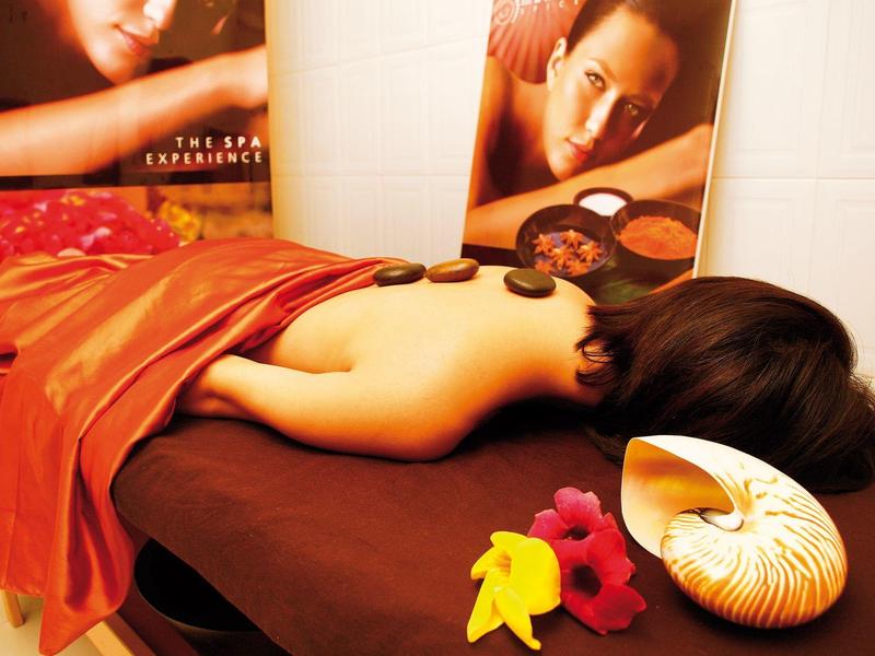 Kobieta leżąca na stole do masażu z gorącymi kamieniami na plecach w relaksującej atmosferze spa.