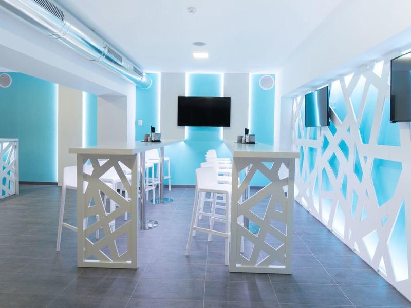 Moderne hotel lobby met blauw-witte geometrische wanden en twee metalen stoelen.