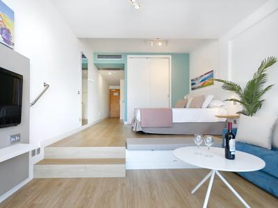 Modern hotel room with sofa, table, double bed, and flat-screen TV.