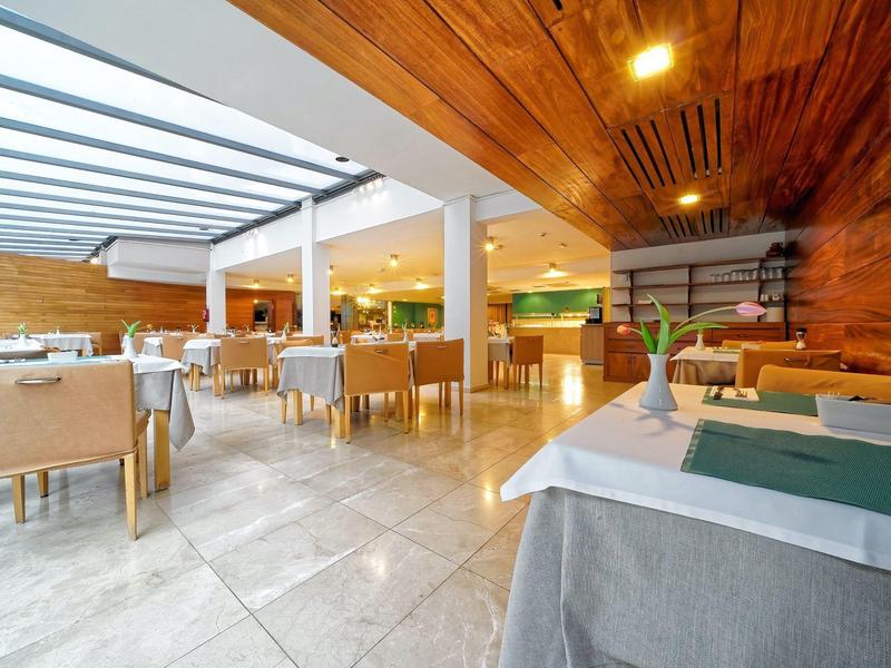 Restaurant lumineux avec murs en bois, chaises beige et tables dressées.