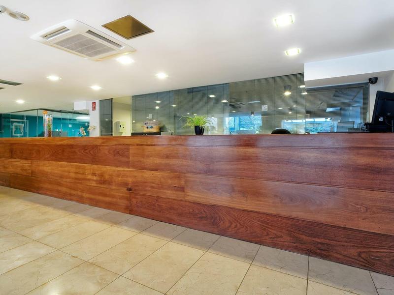 Comptoir de réception d'hôtel moderne en bois avec sol carrelé et éclairage lumineux.