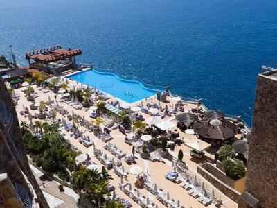 Vue d'une piscine d'hôtel et de chaises longues au bord de la mer sur une côte ensoleillée.