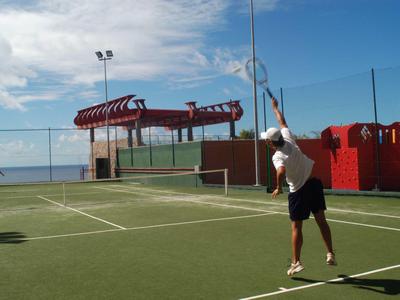 Personne joue au tennis sur un court extérieur près de la mer sous un ciel bleu.