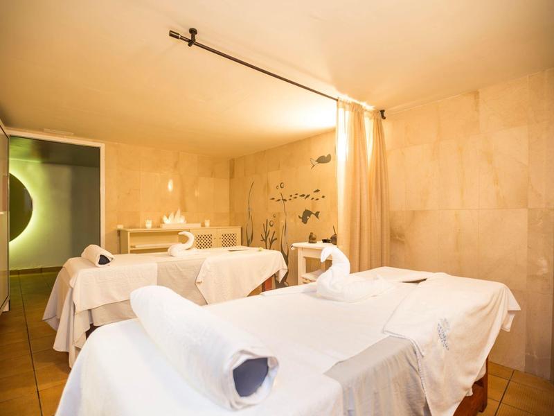 Helles Spa mit zwei weißen Massageliegen, sanfter Beleuchtung und weichen beige Wänden.