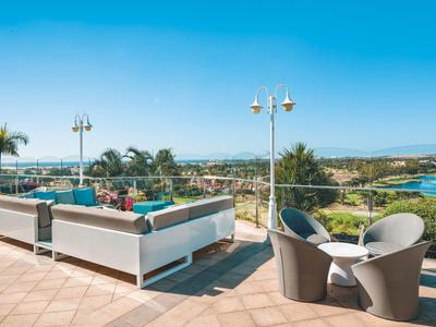 Espace extérieur avec mobilier de jardin moderne, vue sur la mer et ciel dégagé.