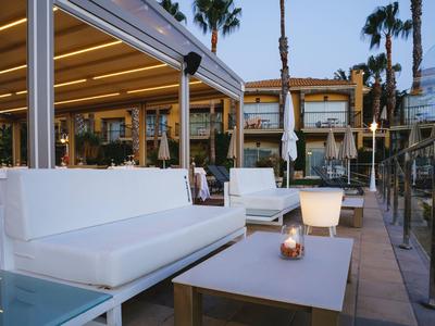 Salon moderne avec canapés blancs et lumière de bougie dans un espace extérieur d'hôtel au crépuscule.