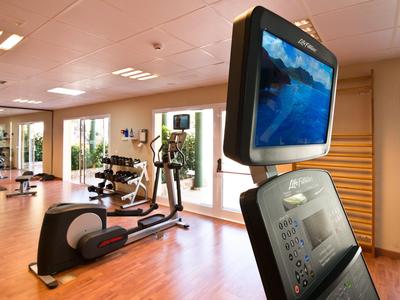 Fitnessraum mit Trainingsgeräten und großen Fenstern im Hotel