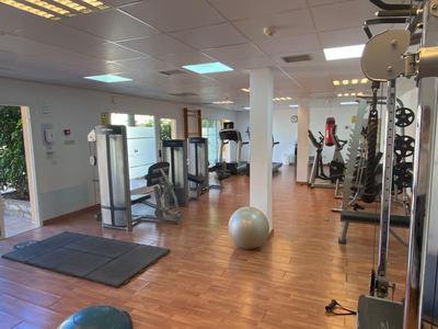 Moderner Fitnessraum mit Holzboden, Trainingsgeräten und Gymnastikmatte in einem Hotel.