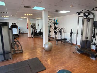 Fitnessraum mit verschiedenen Trainingsgeräten und Holzfußboden in einem Hotel.