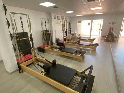 Innenraum eines Studios mit mehreren Pilates-Reformern in Reihe.