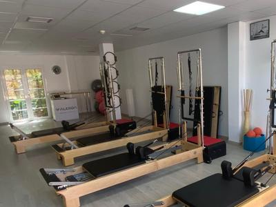 Fitnessraum mit mehreren Pilates-Reformer-Geräten und großer Fensterfront