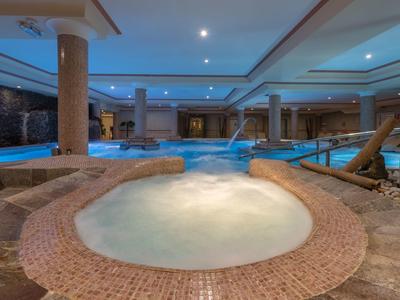 Espace spa intérieur de luxe avec un jacuzzi au premier plan et plusieurs colonnes.