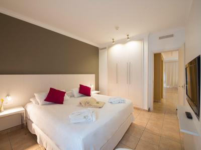 Chambre d'hôtel moderne avec lit double, murs blancs et sol carrelé.