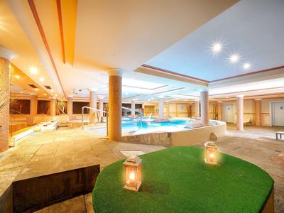 Espace bien-être lumineux et moderne avec piscine, chaises longues et éclairage d'ambiance.