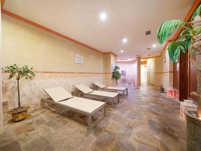 Salle de repos avec chaises longues, plantes et lumière tamisée dans un hôtel.