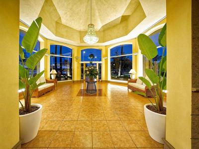 Entrée du hall d'hôtel bien éclairée avec des plantes, fenêtres et espaces de sièges la nuit.