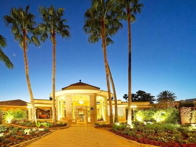 Entrée d'un bâtiment éclairé avec de grands palmiers au crépuscule.