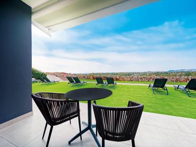 Vue depuis une terrasse avec table et chaises sur des chaises longues et un vaste paysage.