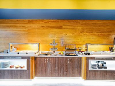 Buffet avec différents plats de petit-déjeuner et viennoiseries chaudes dans un hôtel moderne.