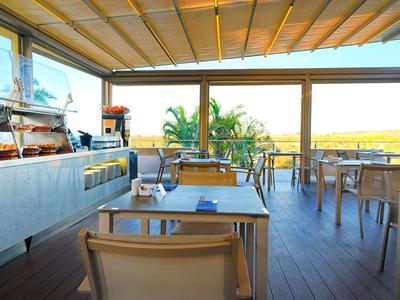 Caffè luminoso e moderno con vista panoramica su palme e paesaggio sullo sfondo.