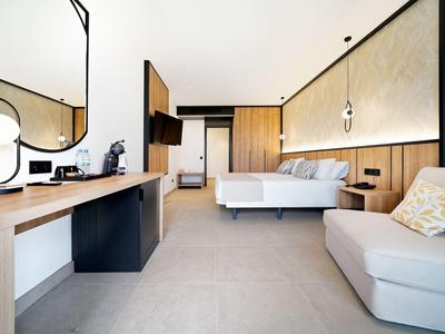 Camera d'hotel moderna con divano, dettagli in legno e grande specchio.