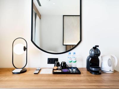 Scrivania d'hotel moderna con lampada, specchio e macchina per il caffè su superficie in legno.