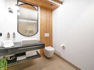 Bagno moderno con lavabo, WC sospeso e pannelli in legno a parete.