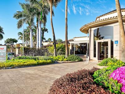 Hotel con architettura moderna e giardino tropicale sotto un cielo azzurro