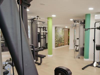 Interno di una palestra moderna in hotel con attrezzature per il fitness e illuminazione luminosa.