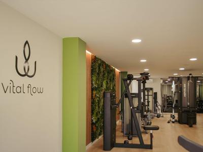 Palestra moderna con vari attrezzi per allenamento e parete verde.