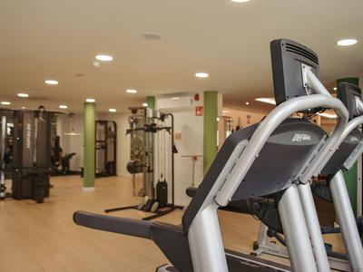 Palestra moderna con varie attrezzature per allenamento e pavimento in legno chiaro.