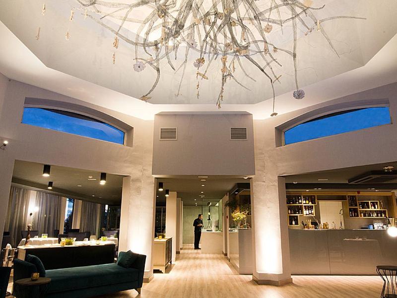 Espace lounge d'hôtel élégant avec lustre moderne et pouf coloré.