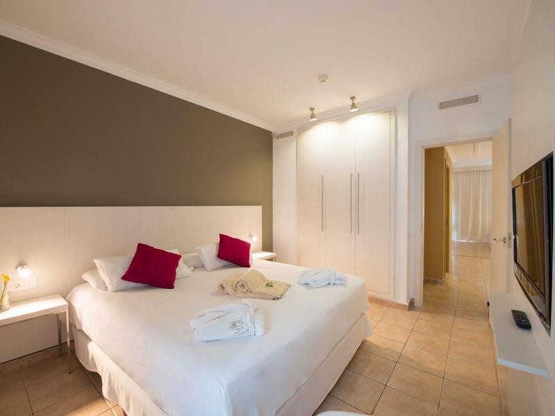 Chambre d'hôtel moderne avec lit double, murs blancs et sol carrelé.