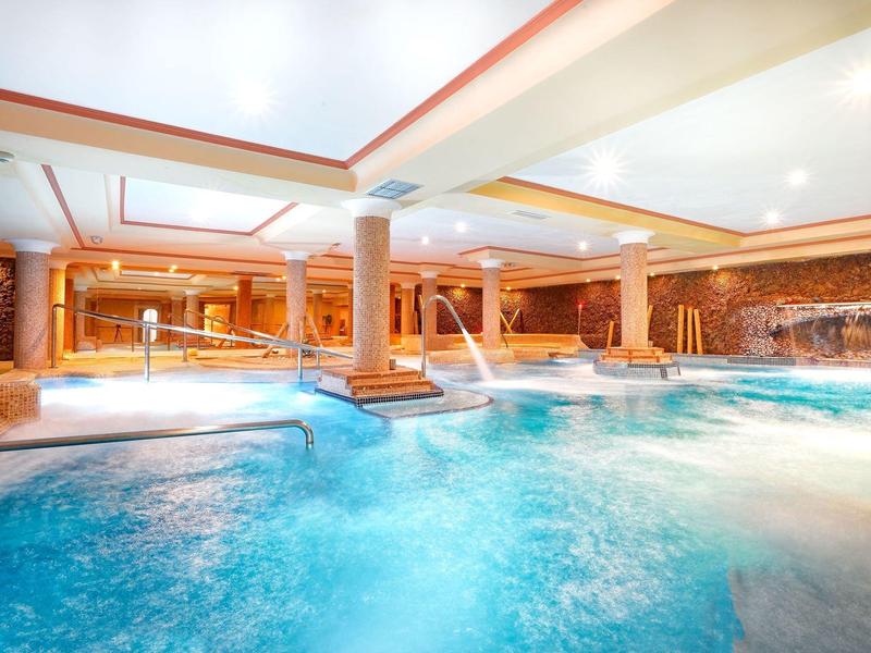 Une piscine intérieure luxueuse avec massages aquatiques et cascades dans une ambiance détendue.