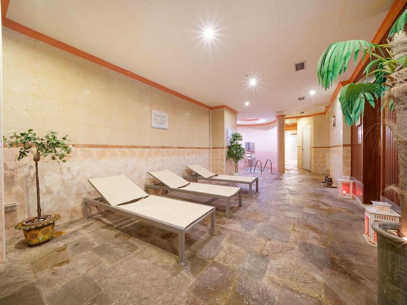 Salle de repos avec chaises longues, plantes et lumière tamisée dans un hôtel.