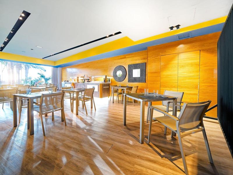 Restaurant moderne et lumineux avec sol en bois et accents jaunes.