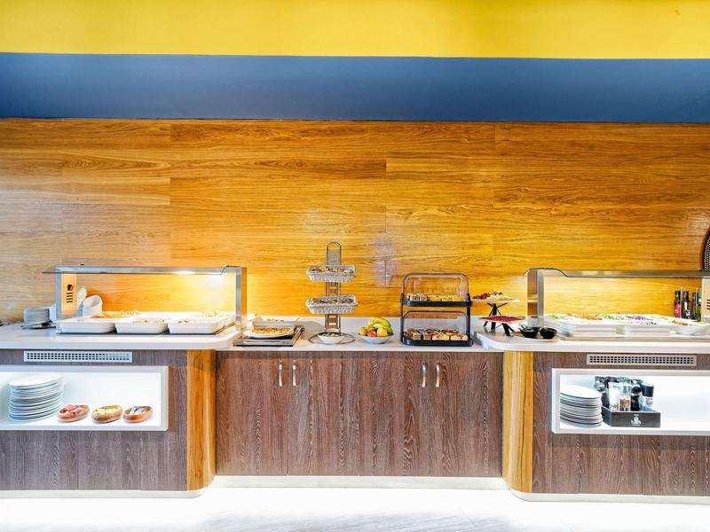 Buffet avec différents plats de petit-déjeuner et viennoiseries chaudes dans un hôtel moderne.