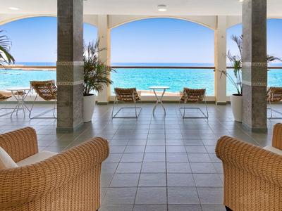 Spazio relax aperto con poltrone in vimini e vista sul mare blu.