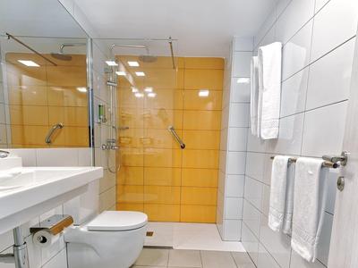 Salle de bains moderne avec douche à paroi vitrée et carrelage orange vif.