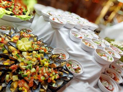 Buffet gastronomique avec fruits de mer et salades, présenté sur nappes blanches.