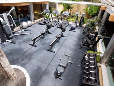 Moderner Fitnessraum mit verschiedenen Trainingsgeräten und ausgestatteten Bereichen für Kraft- und Ausdauertraining.