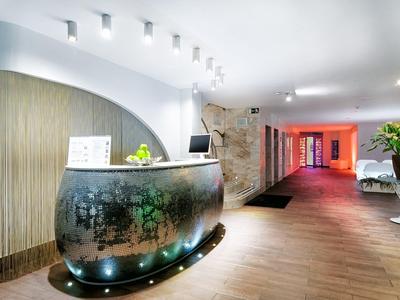 Réception d'hôtel moderne avec comptoir incurvé, éclairage doux et plantes décoratives.