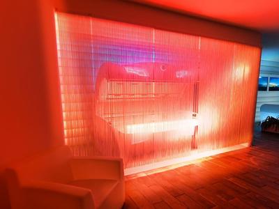 Mur lumineux rouge dans une chambre moderne avec plancher en bois et meuble blanc.