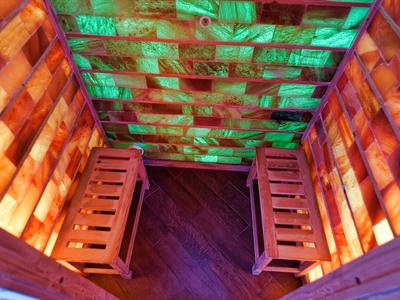 Petite cabine en bois avec lumière d'ambiance verte et bancs en bois.