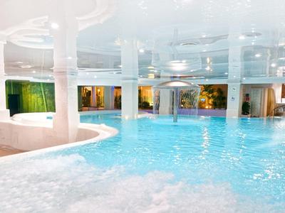 Piscine intérieure avec eau turquoise et colonne blanche, ambiance lumineuse et relaxante.