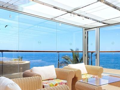 Terrasse d'hôtel confortable avec vue dégagée sur la mer et fauteuils en osier beige.