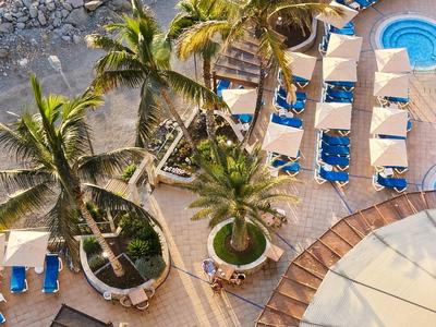 Palmiers, chaises longues, piscines et sable, vue aérienne d'une zone de détente de vacances.