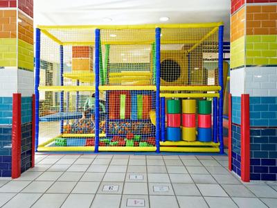 Structure de jeu colorée avec filets et tubes dans une aire de loisirs intérieure.