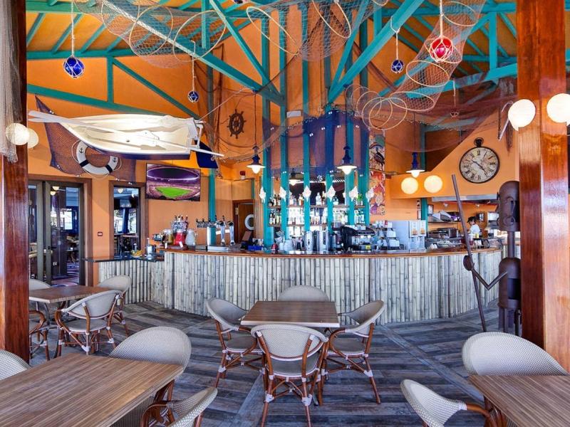 Intérieur lumineux de bar avec mobilier en bois et ambiance tropicale.